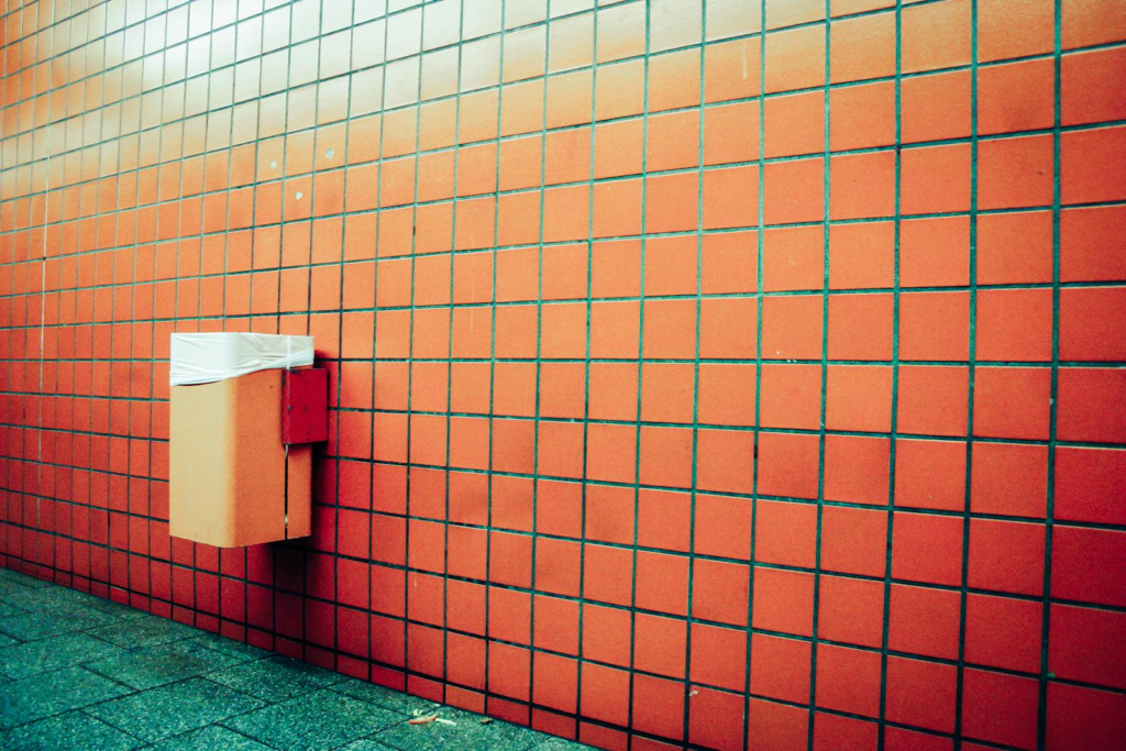 Trash can on tile wall, symbolizing the environmental impact of EpiPens