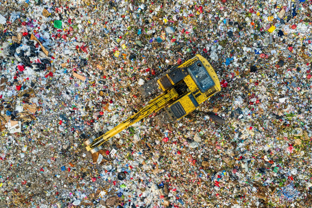 Crane lifting trash in a field, representing EpiPen's unsustainable waste