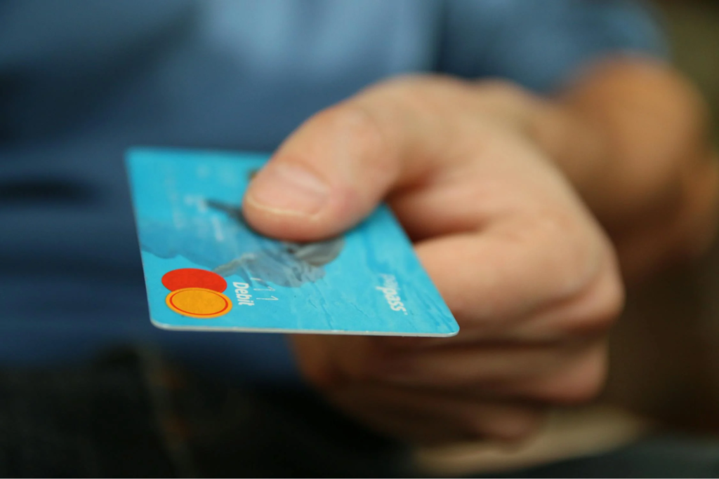 Close-up of hand holding blue debit card, symbolizing the cost of EpiPens